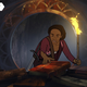 A young animated woman explores a pile of books, reaching out to a mysterious tome with one hand while her other holds a flaming torch.